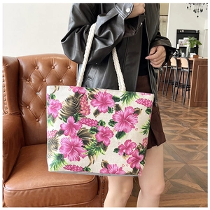 Ethnic canvas tote bag with hibiscus flower print and rope handle on model's shoulder