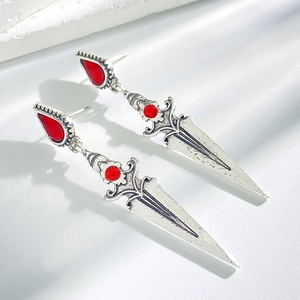 Detailed macro view of Gothic silver sword earrings with red gemstones on white background