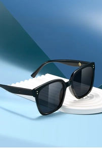 Detail of black square sunglasses with gold metal accents and gradient grey lenses