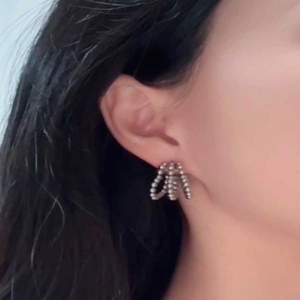 Close-up of multi-layer C-shape silver earrings with bead inlay on a model's ear
