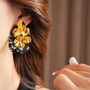 Detailed view of a vintage metal flower and leaf earring worn by a model
