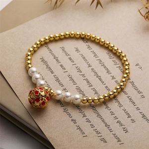 Détail d'un bracelet perlé doré avec perles blanches et pendentif étoile rouge sur livre