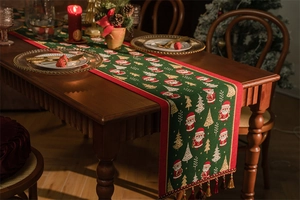 Detail of green Christmas table runner with jacquard Santa Claus motifs and red tassels