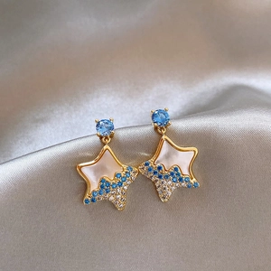 Detail view of star-shaped stud earrings with blue crystals and elegant gold-tone finish