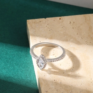 Macro shot of silver ring with marquise-cut gemstone on a textured beige stone background