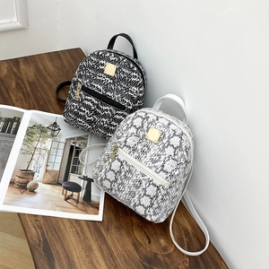 Detail of mini backpacks in black tweed and white snakeskin with gold hardware