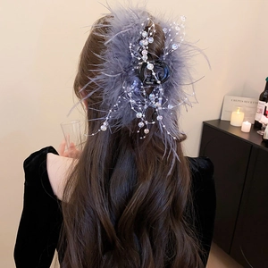 Detail view of a luxury grey feather hair claw clip with beads on a model's hair