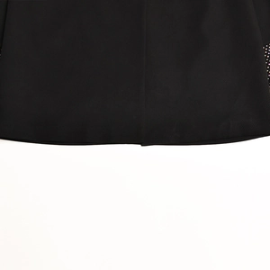 Dettaglio dell'orlo del blazer nero con strass scintillanti e trama di tessuto opaco