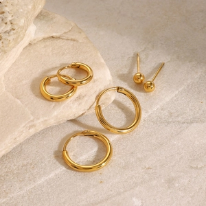 Detailed set of gold stainless steel hoop earrings and studs on natural stone
