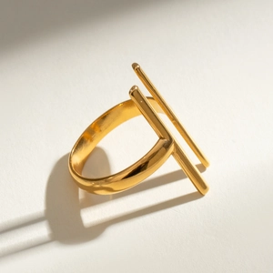 Close-up of a minimalist double-bar gold stainless steel ring on a textured background