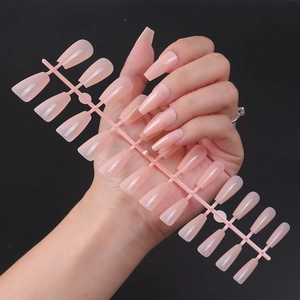 Close-up of glossy nude pink coffin-shaped press-on nails on a plastic display stand
