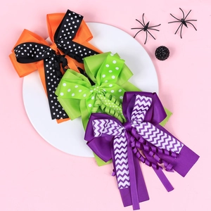 Three Halloween layered bow hair clips with polka dots and spider decor on a white plate