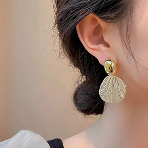 French vintage scallop shell earrings with gold metallic texture worn by a model