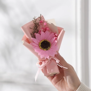 Close-up of a handmade mini artificial sunflower bouquet wrapped in elegant pink paper