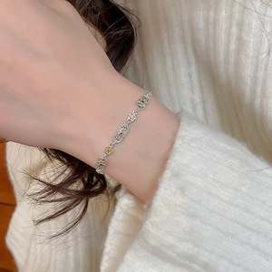Close-up of a silver-toned floral bracelet with colorful enamel petals on a wrist