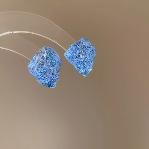 Detailed macro view of irregular blue resin stud earrings with a multifaceted crystal texture