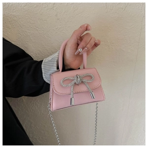 Detail of pink mini PU bag featuring a sparkling silver rhinestone bow and chain strap