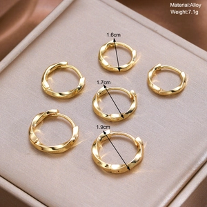 Detailed view of three pairs of gold twisted alloy hoop earrings in various sizes