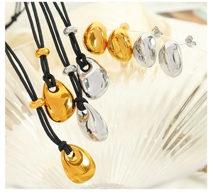 Macro shot of gold and silver teardrop pendants and earrings in a glass bowl