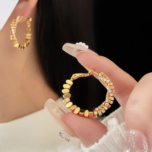 Detail of gold oval earring with half-polished metal and half-pave set sparkling cubic zirconia