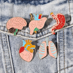 Set of 5 pink anatomical organ enamel pins on a denim jacket including heart and brain