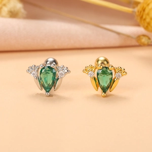 Détail de boucles d'oreilles cartilage en or et argent avec pierres vertes en goutte