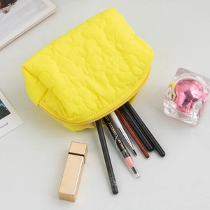 Detail of yellow quilted makeup bag showing flower stitching and cosmetics storage
