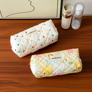 Detailed view of quilted cotton pencil cases with floral and polka dot patterns on wood