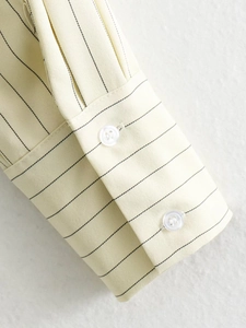 Close-up of light yellow striped shirt cuff with two white buttons and twill texture
