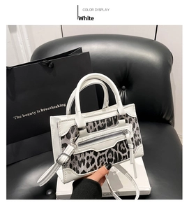 Detalle del bolso de cuero blanco con paneles de leopardo y detalles de cremallera