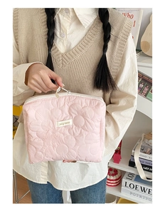 Gros plan d'une trousse de maquillage rose matelassée aux motifs floraux stylisés