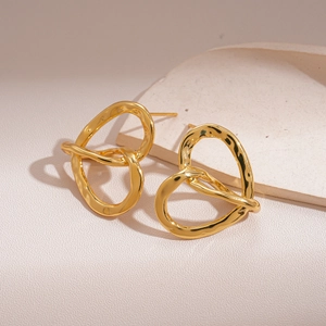Detail of 18k gold plated hollow heart-shaped knotted earrings on stone display