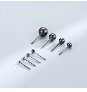 Macro view of eight black S925 sterling silver ball studs in various sizes on grey background