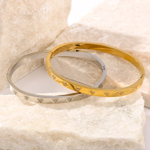 Polished 18K gold and silver heart-shaped bangles with crystals on natural stone