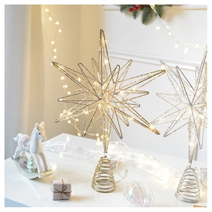 Close-up of iron Christmas tree star toppers in gold and silver with warm LED lights