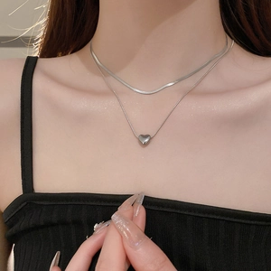 Close-up of minimalist double-layered silver heart necklace worn on a woman's collarbone