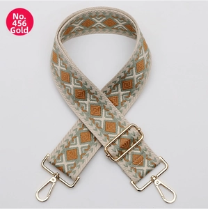 Detailed view of bohemian style woven bag strap with golden metal hardware buckles