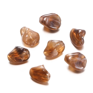 Macro view of irregular amber acrylic beads with white marble texture for DIY jewelry