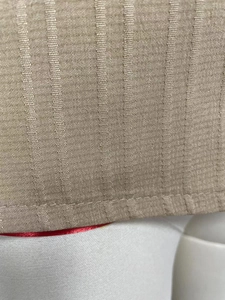Detailed macro shot of khaki woven fabric showing vertical texture and stitching on the hem