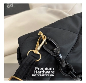 Close-up of golden metal twist lock and black chain on quilted nylon shoulder bag
