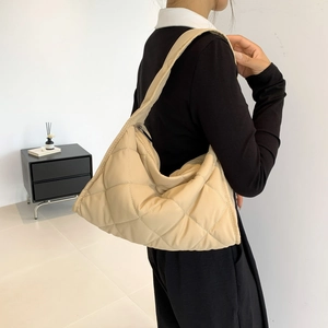 Detail of beige quilted nylon puffer shoulder bag with a wide strap and zip closure