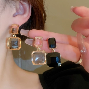Macro shot of geometric crystal drop earrings with gold-plated prong settings and vibrant facets