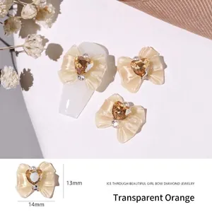Detail of 14mm translucent orange resin bow nail charm with a heart-shaped rhinestone