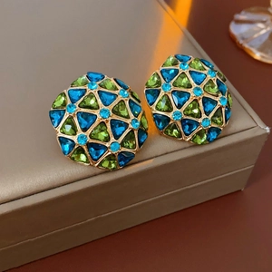 Macro shot of vintage gold dome earrings with green and blue geometric crystals