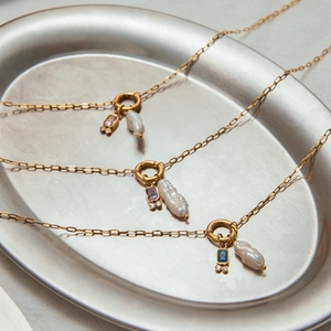 Detailed top view of gold necklaces with baroque pearls and colorful gemstone charms