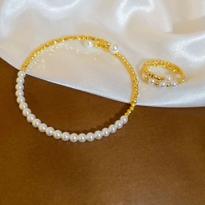 Detail of beaded jewelry set with white faux pearls and golden beads on silk