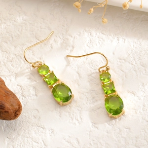 Detail of emerald green crystal drop earrings with golden multi-shape geometric gems