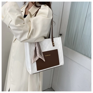 Close-up of white woven tote bag with brown pocket and stylish decorative silk scarf