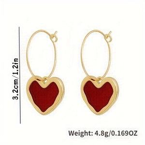 Detail view of gold heart earrings with red enamel inlay and size weight specifications