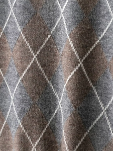 Detailed macro view of argyle pattern wool blend knit fabric in grey and beige tones